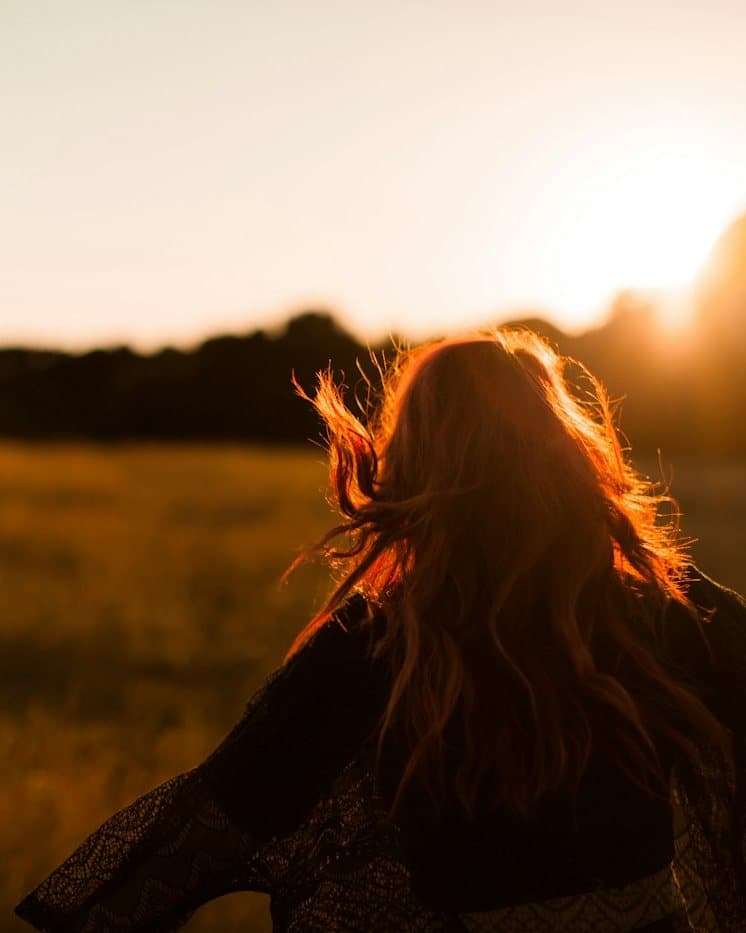A woman standing in an open field at golden hour, representing recovery from trauma and PTSD